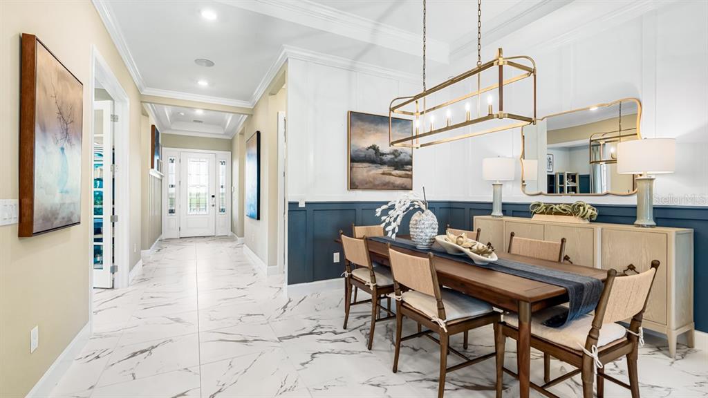 A dining room features a wooden table, chairs, a sideboard, and white marble-look tile flooring — 7825 CORAL SEA LANE, PALMETTO, FL