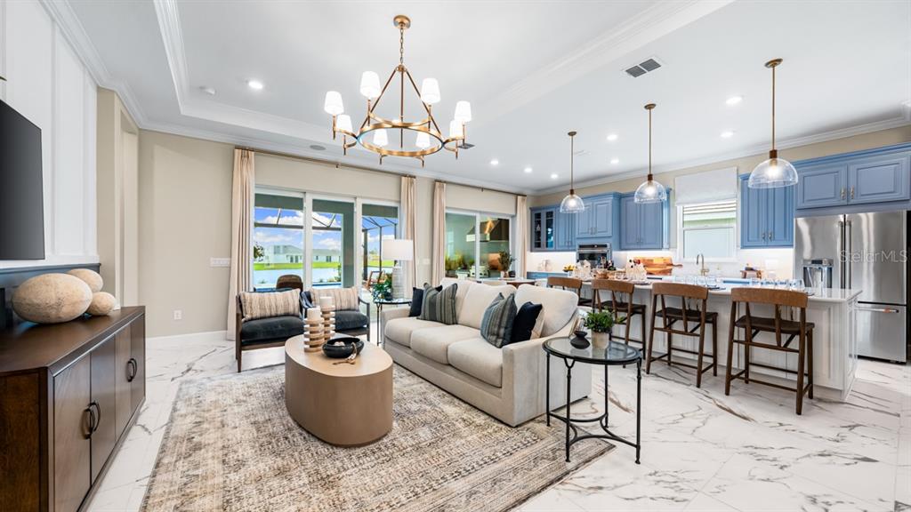 A living room and kitchen open-concept space features marble floors, blue cabinets, and a chandelier — 7825 CORAL SEA LANE, PALMETTO, FL