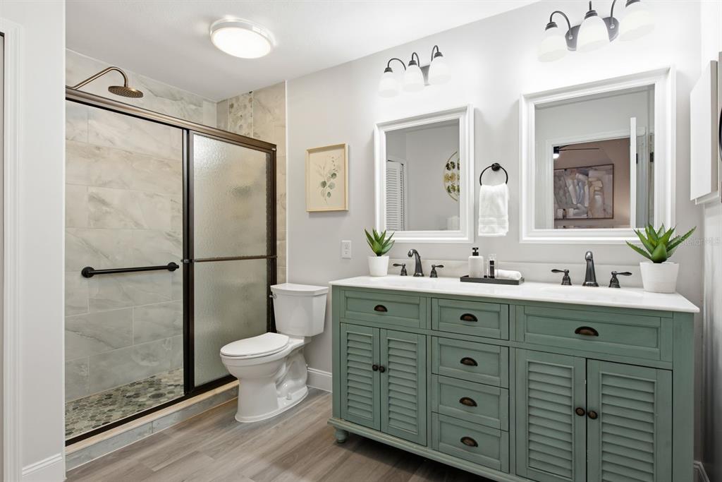 A bathroom features a green double vanity, a walk-in shower, and a white toilet — 2767 VANESSA LANE, PALM HARBOR, FL
