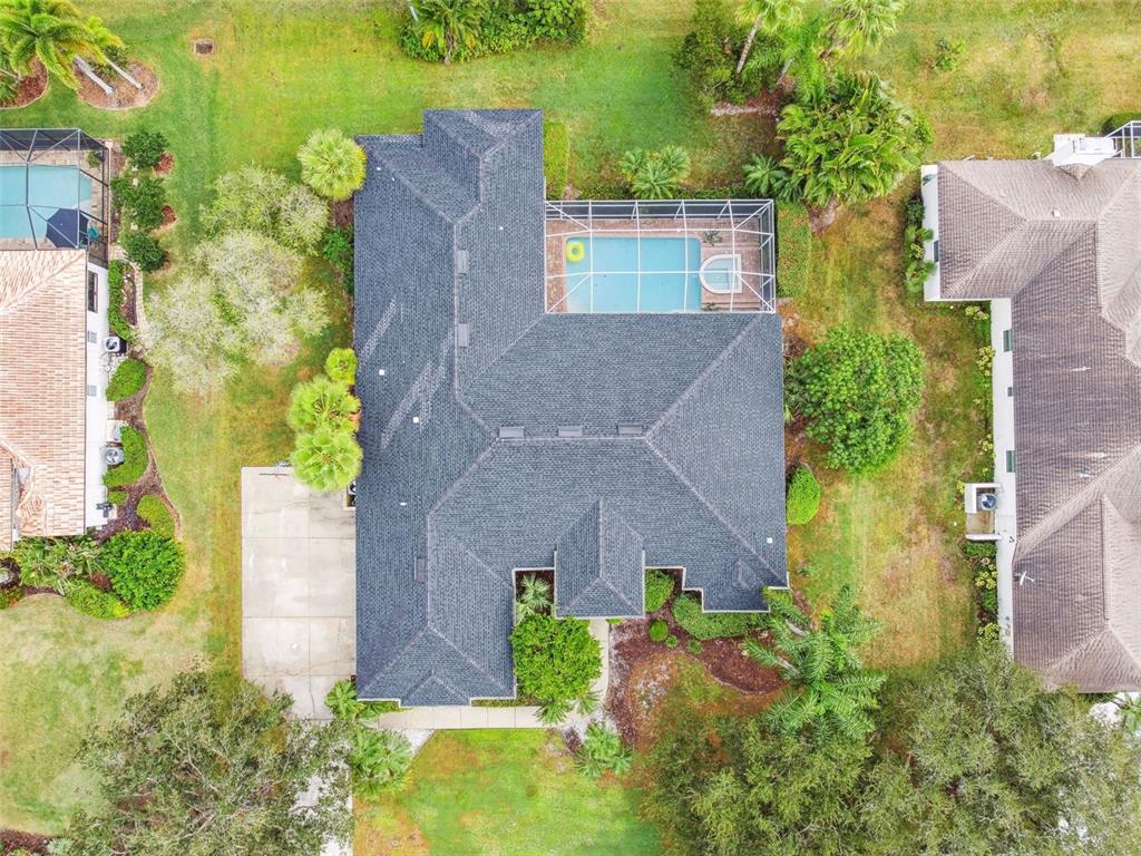 An aerial view shows a house with a dark shingled roof and a screened-in pool — 7650 PARTRIDGE STREET CIRCLE, BRADENTON, FL