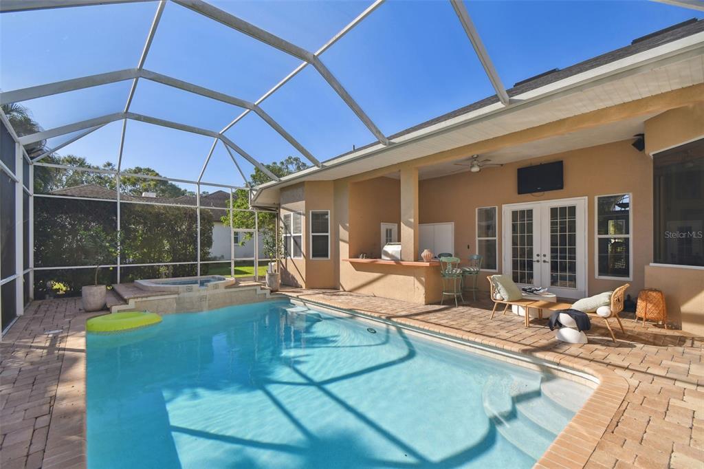 A screened-in patio features a swimming pool, a raised spa, and a potted lemon tree — 7650 PARTRIDGE STREET CIRCLE, BRADENTON, FL