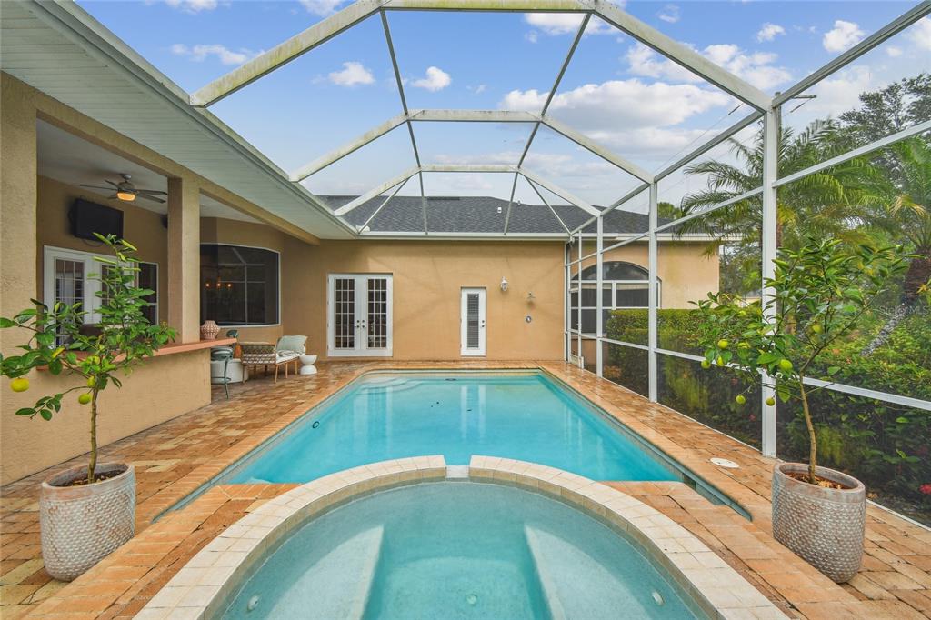 A screened-in patio features a swimming pool, a spa, and an outdoor bar area — 7650 PARTRIDGE STREET CIRCLE, BRADENTON, FL