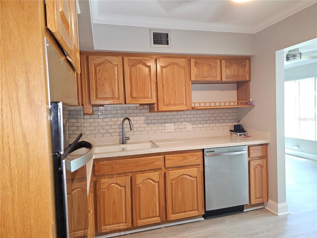 A kitchen features oak cabinets, a white subway tile backsplash, and stainless steel appliances — 2321 ECUADORIAN WAY UNIT 31, CLEARWATER, FL