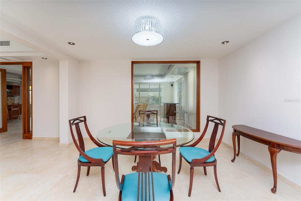 A dining room features a glass-topped table, three wooden chairs, and a large window — 254 SABANERA, DORADO, PR