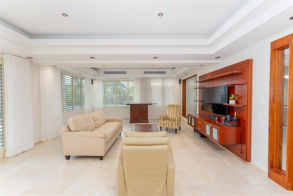 A living room features a beige sofa, a recliner, and a wooden media wall unit — 254 SABANERA, DORADO, PR