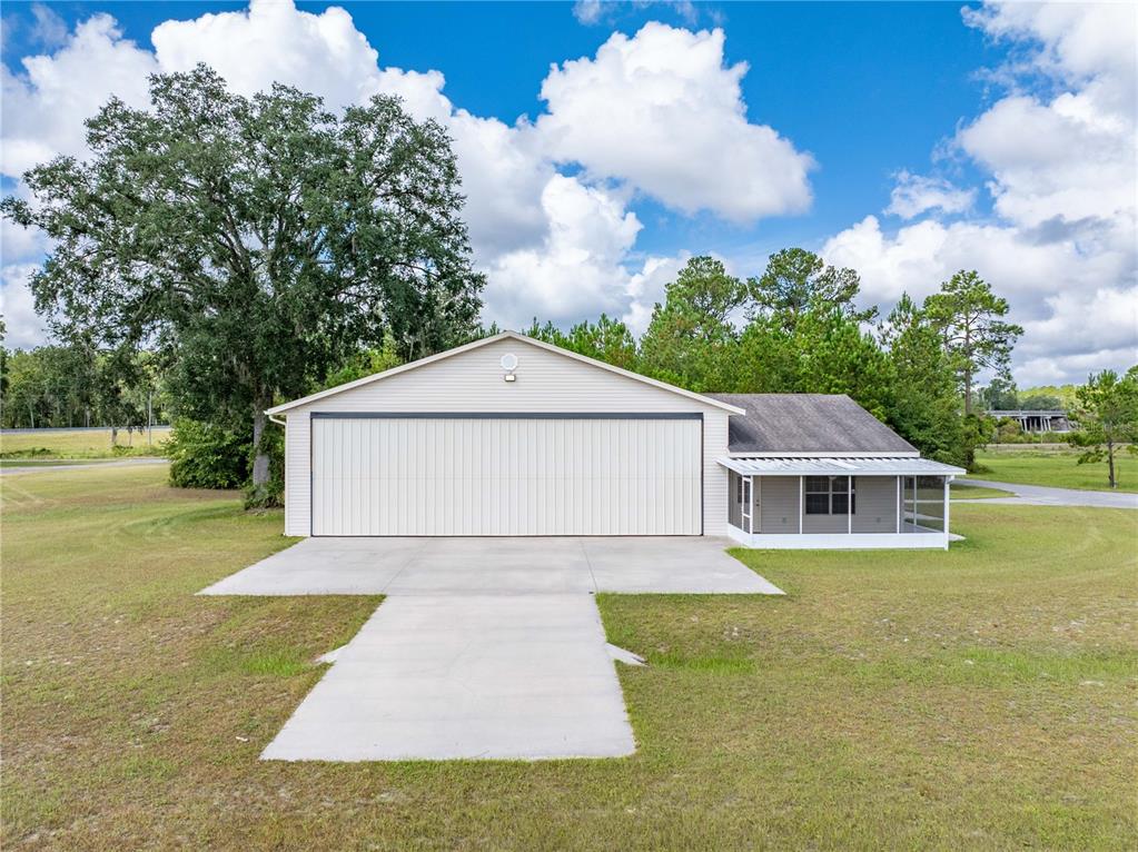 A large hangar-style building with a concrete driveway and an attached screened-in porch — 168 SW POBEREZNY GLN, LAKE CITY, FL