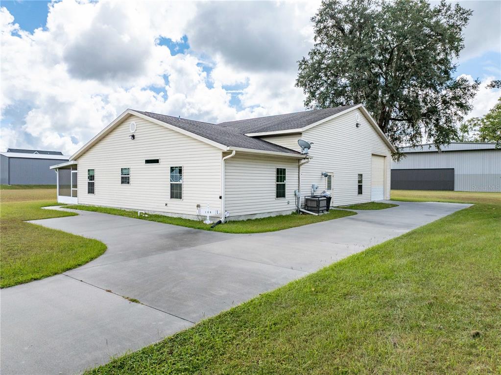 A side view of a beige, single-story house with a concrete driveway and large tree — 168 SW POBEREZNY GLN, LAKE CITY, FL