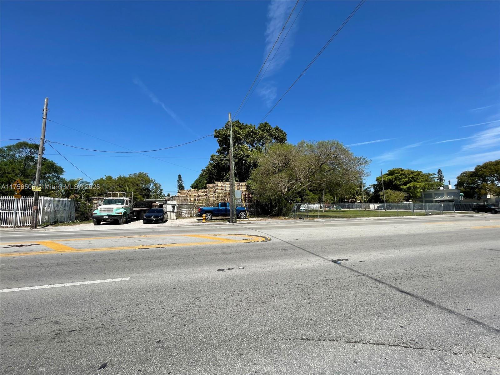A view of a vacant lot with a stack of pallets and parked vehicles — 3013 NW 54th St, Miami FL 33142, MIAMI, FL