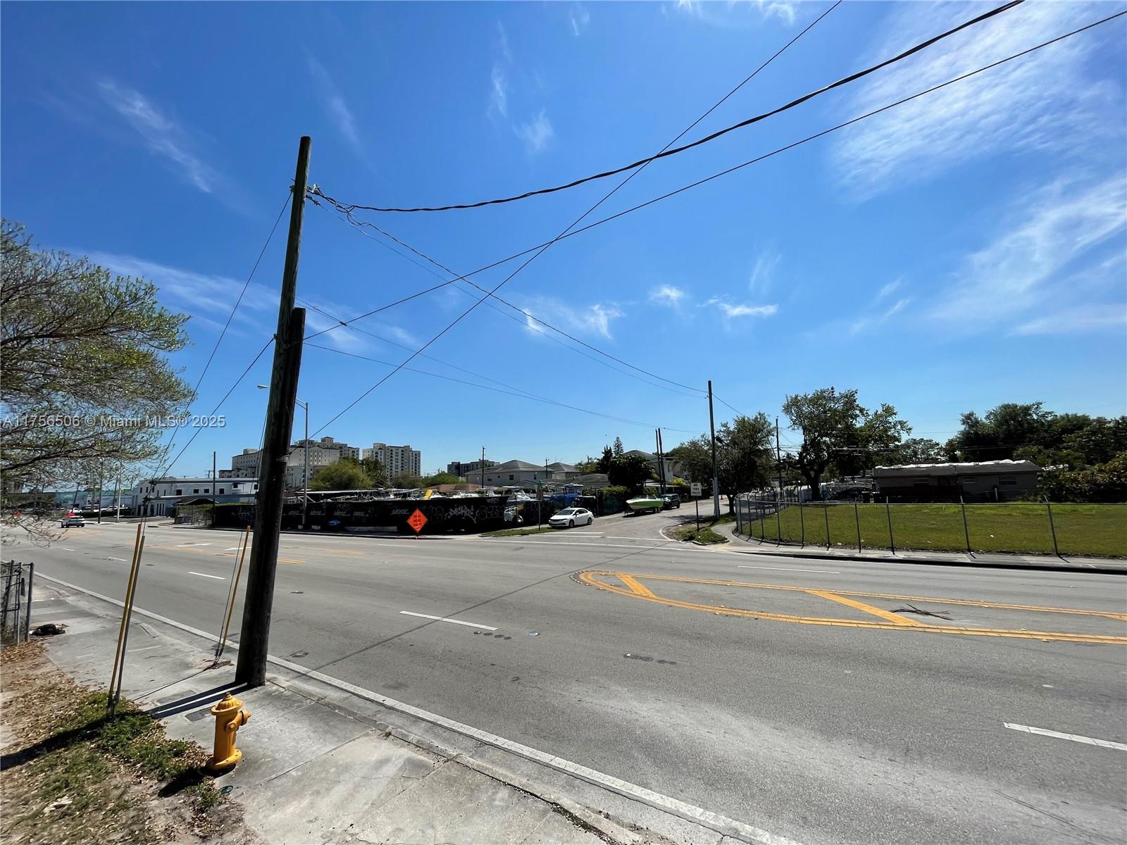 A view of a paved intersection with a utility pole, fire hydrant, and fenced lot — 3013 NW 54th St, Miami FL 33142, MIAMI, FL