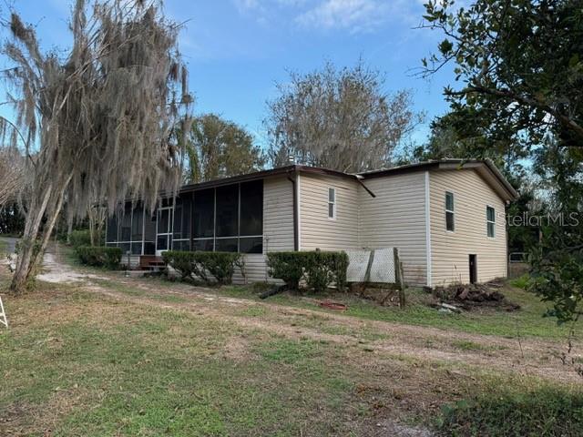 A single-story house with light-colored siding and a screened-in porch sits on a grassy lot — 14914 SE 56TH AVENUE, SUMMERFIELD, FL