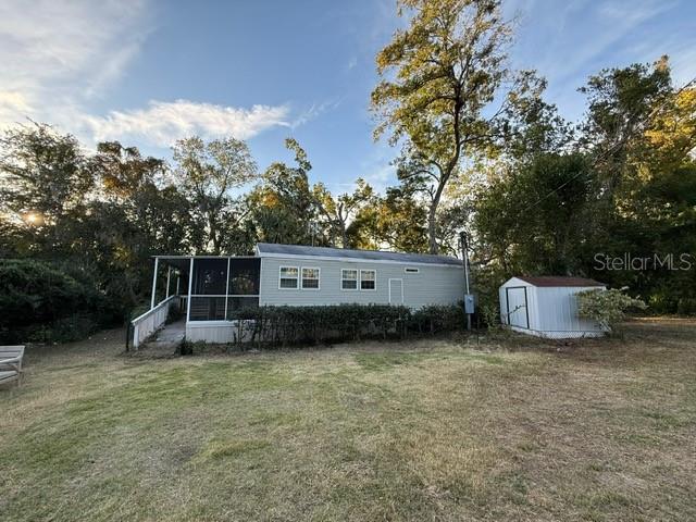 A light-colored mobile home with a screened porch sits next to a small storage shed — 14914 SE 56TH AVENUE, SUMMERFIELD, FL