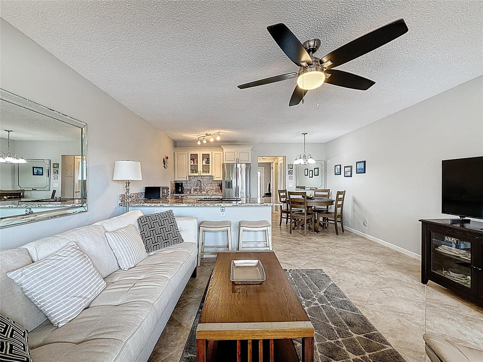 An open-concept living and dining area features a kitchen island, tile flooring, and ceiling fan — 800 SW 11th Avenue # 12, Hallandale Beach FL 33009, HALLANDALE BEACH, FL