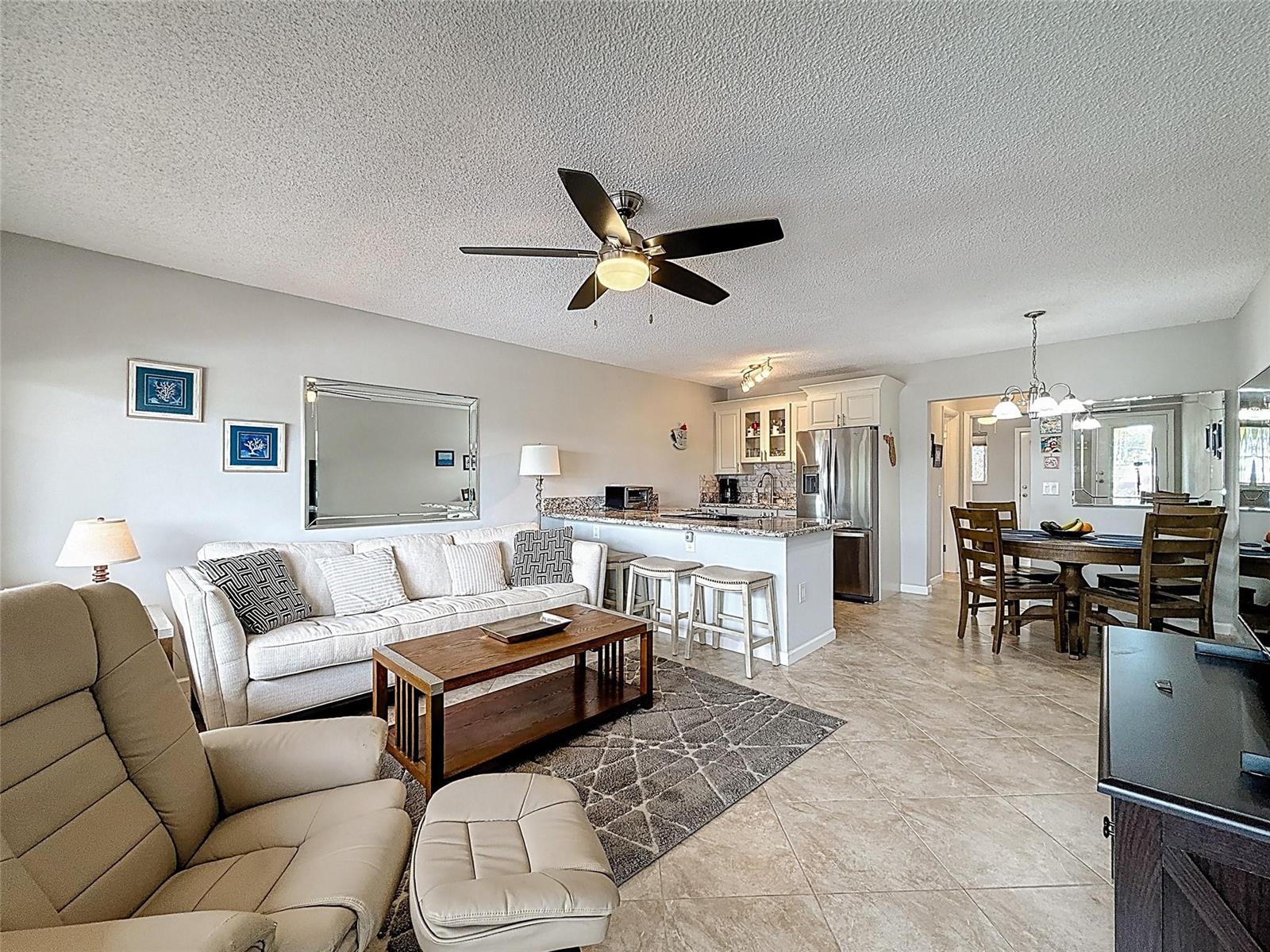 An open-concept living room and kitchen feature tile flooring, a ceiling fan, and neutral furniture — 800 SW 11th Avenue # 12, Hallandale Beach FL 33009, HALLANDALE BEACH, FL