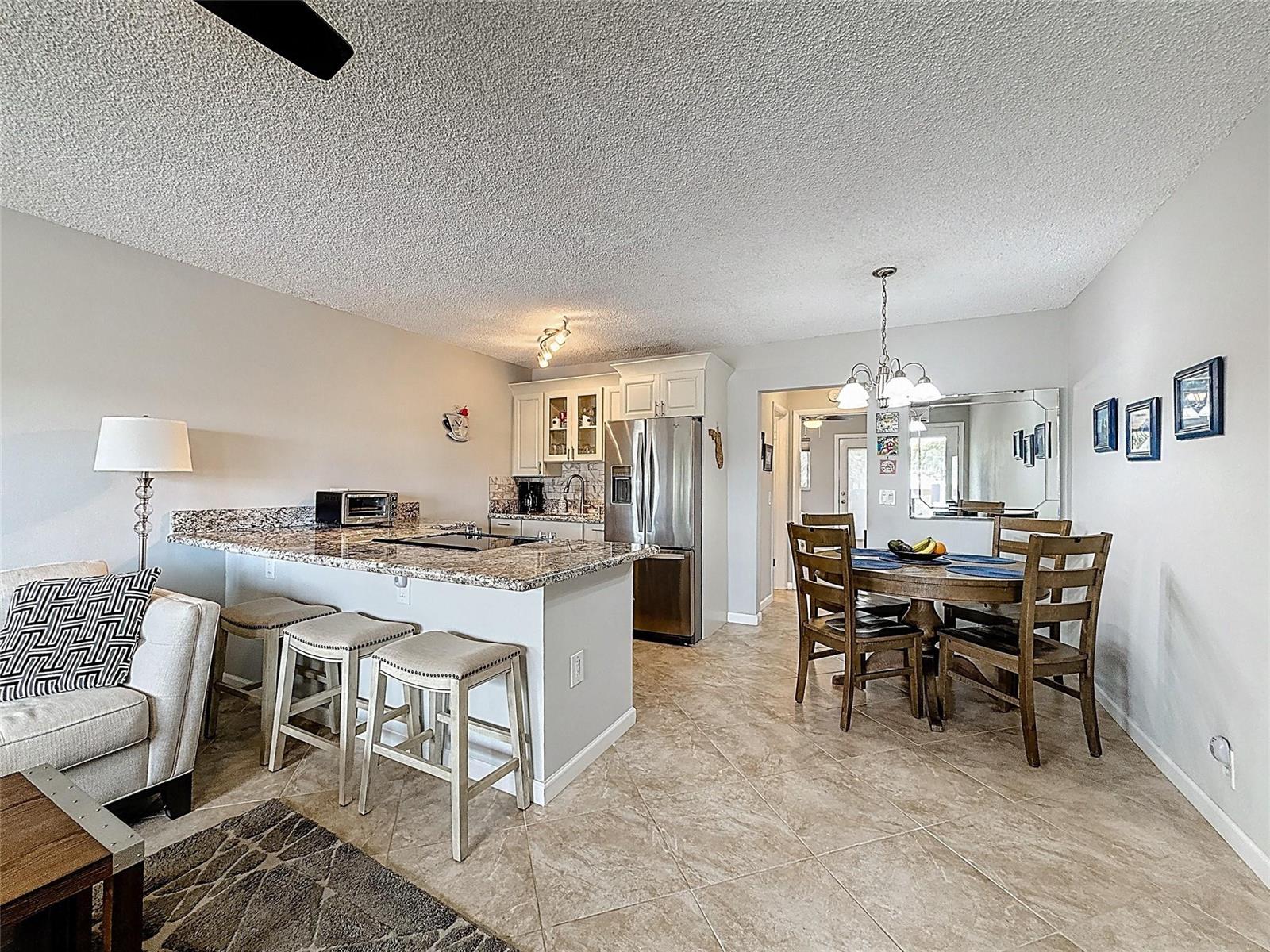 A kitchen with granite countertops and stainless steel appliances opens to a dining area — 800 SW 11th Avenue # 12, Hallandale Beach FL 33009, HALLANDALE BEACH, FL