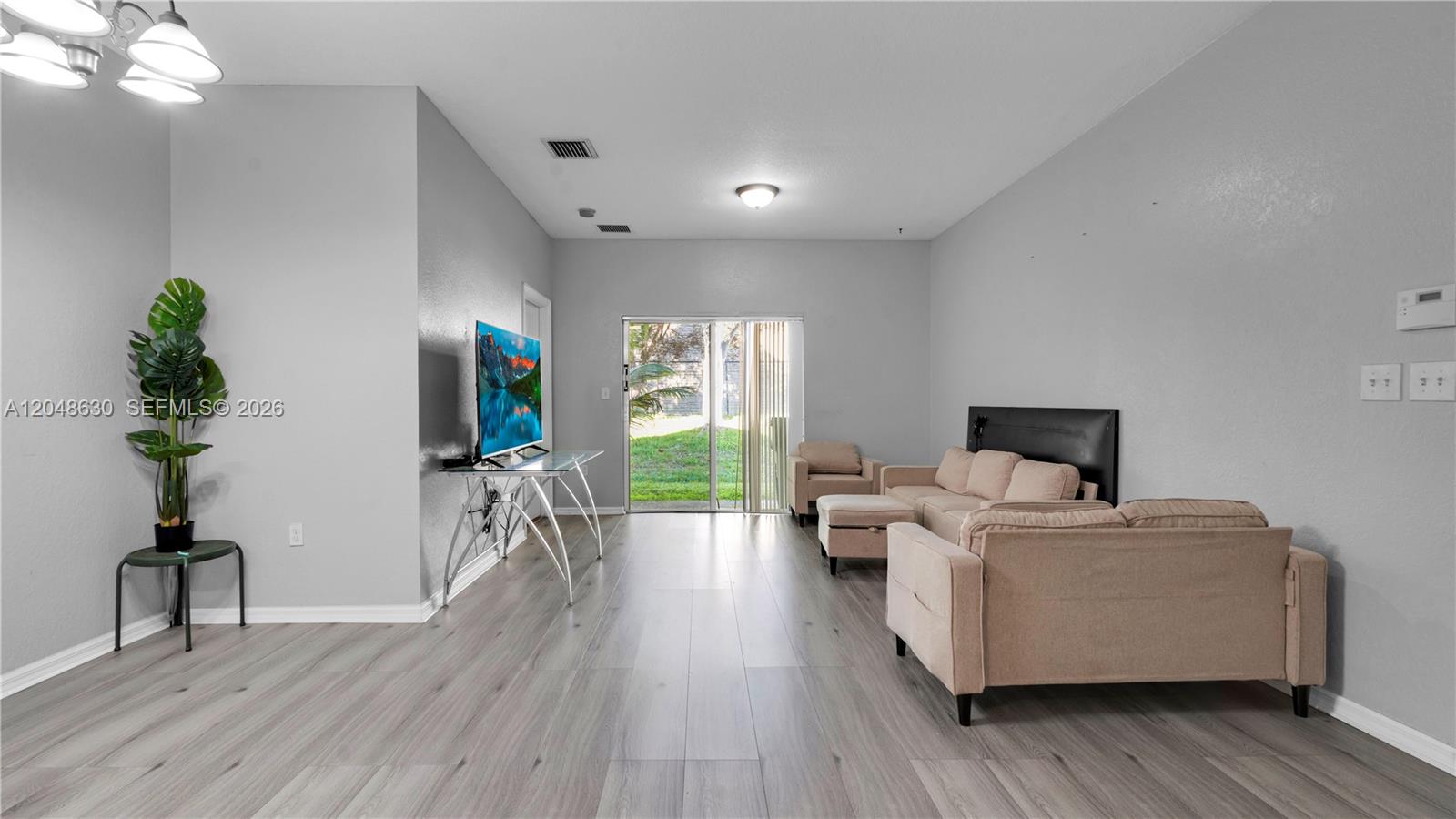 A living room features light gray walls, wood-look flooring, a television, and beige furniture — 13103 SW 42nd St # 5106, Miramar FL 33027, MIRAMAR, FL