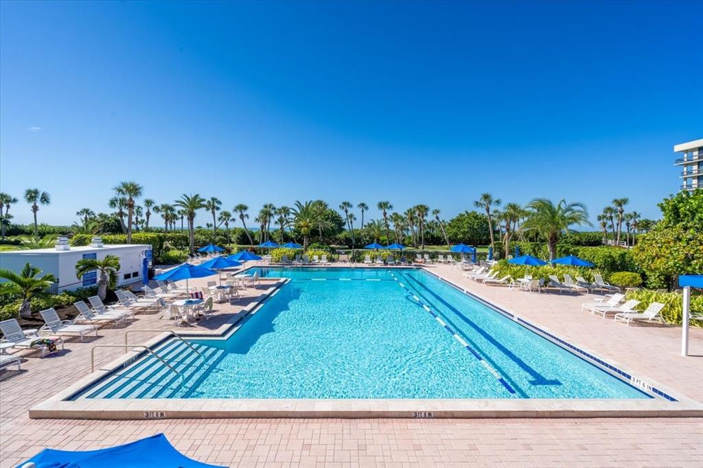 A rectangular swimming pool with blue umbrellas and lounge chairs on a paved deck — 1065 GULF OF MEXICO DRIVE UNIT 305, LONGBOAT KEY, FL