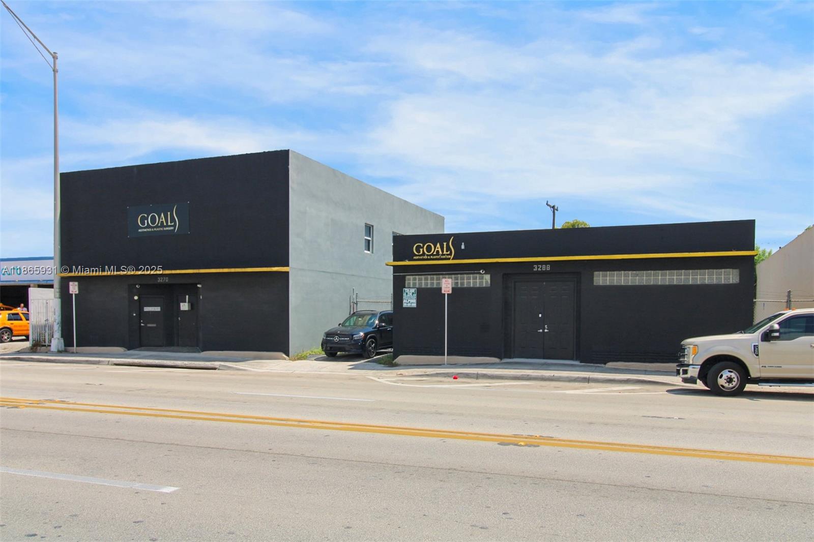 Two adjacent black commercial buildings with yellow trim stand along a paved road — 3270 NW 36th St, Miami FL 33142, MIAMI, FL