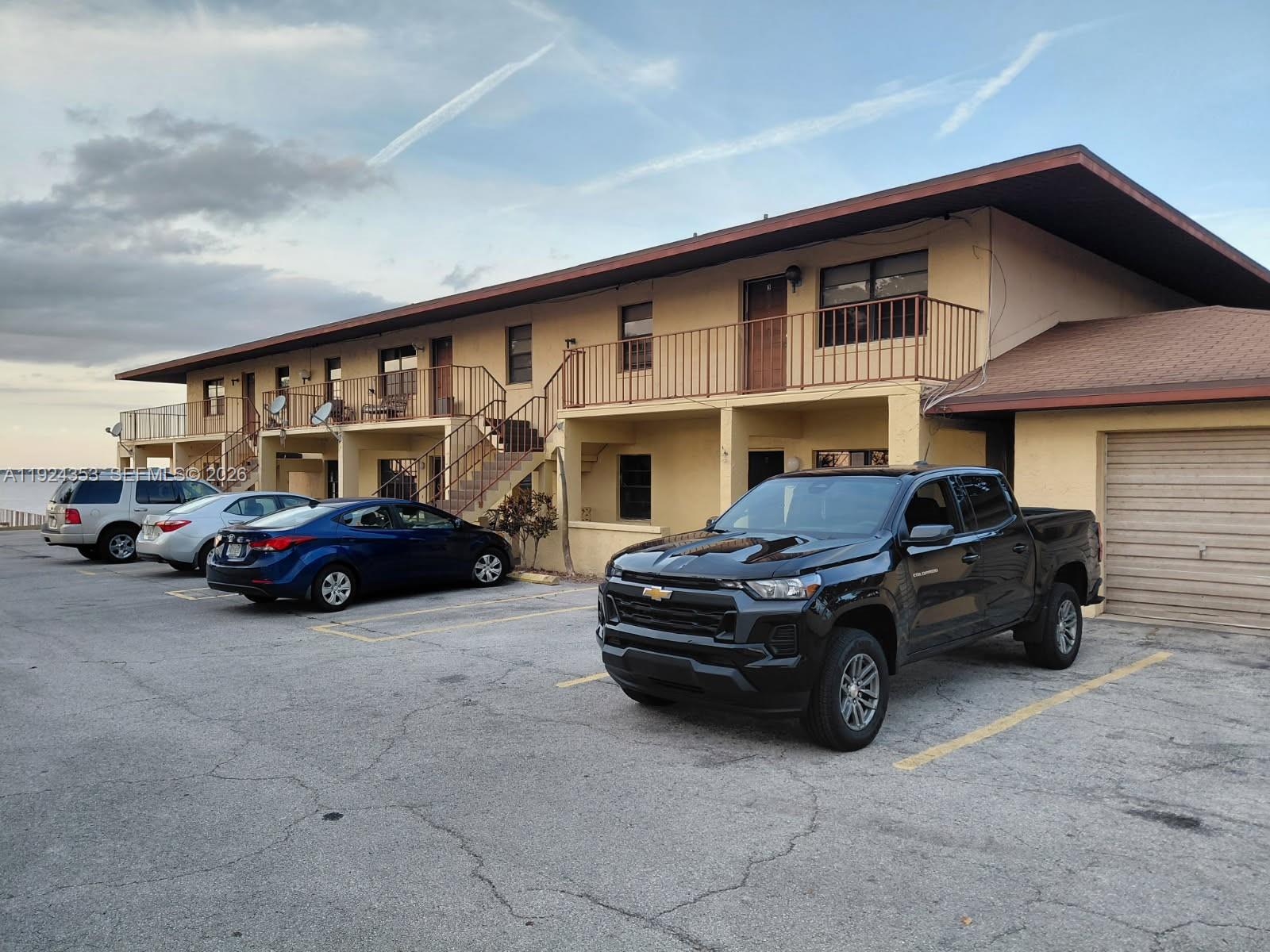 A two-story apartment building with a parking lot and several parked vehicles in front — 1025 LAKEVEIW DRIVE, Sebring FL 33870, SEBRING, FL