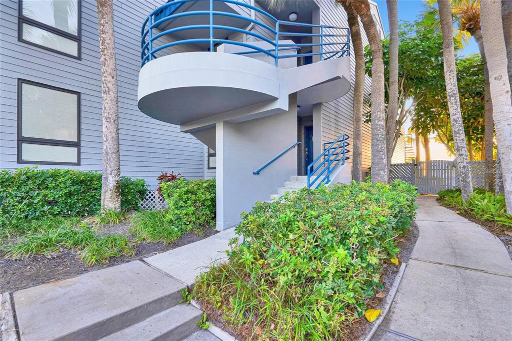 An exterior view of a multi-story building with a curved balcony and concrete stairs — 910 PINELLAS BAYWAY S UNIT 107, TIERRA VERDE, FL