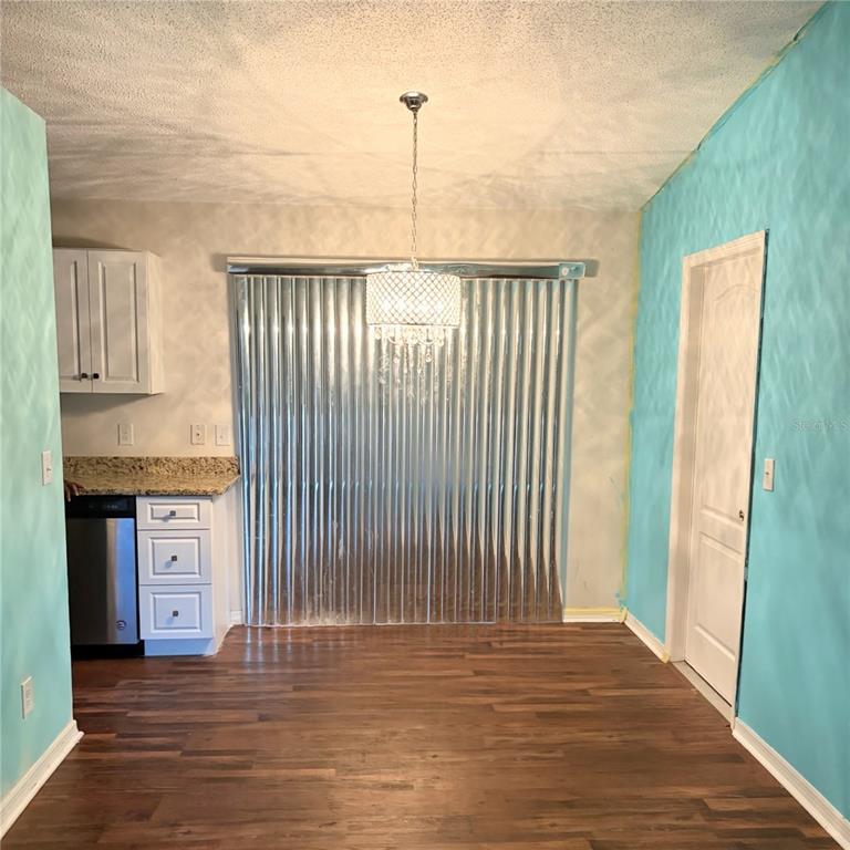 A dining area features wood flooring, turquoise walls, a crystal chandelier, and corrugated metal blinds — 2404 NE 32ND PLACE, OCALA, FL