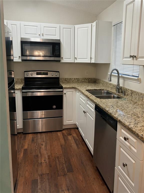 A kitchen features white cabinets, granite countertops, stainless steel appliances, and wood-look flooring — 2404 NE 32ND PLACE, OCALA, FL