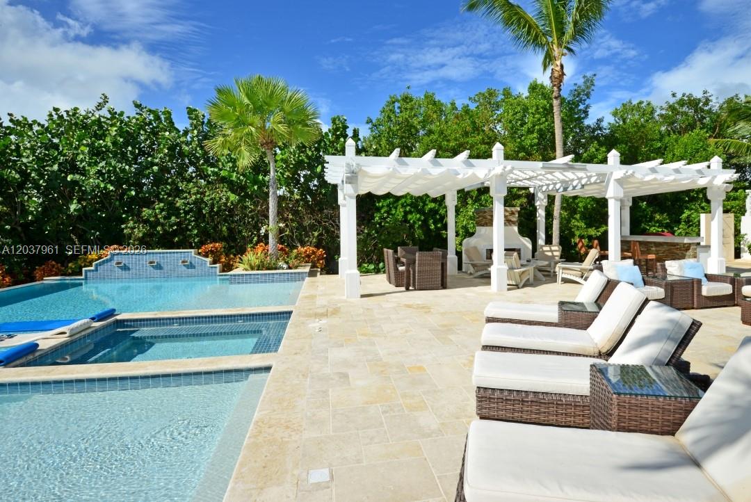 A swimming pool and hot tub sit beside a patio with a white pergola — 0 Juanillo Bay, FL