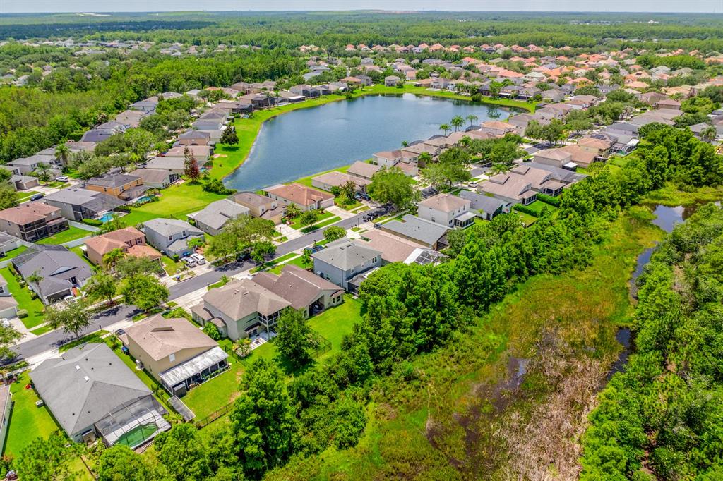 An aerial view shows a suburban neighborhood with houses surrounding a central lake and wetlands — 14933 YORKSHIRE RUN DRIVE, ORLANDO, FL