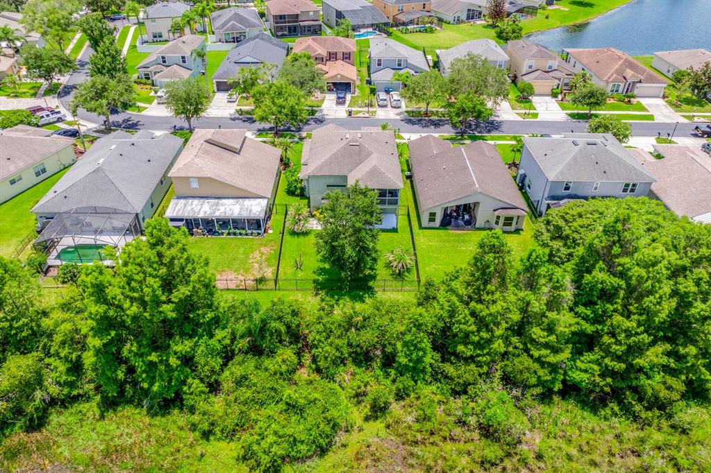 An aerial view shows a row of suburban houses with backyards bordering a wooded area — 14933 YORKSHIRE RUN DRIVE, ORLANDO, FL