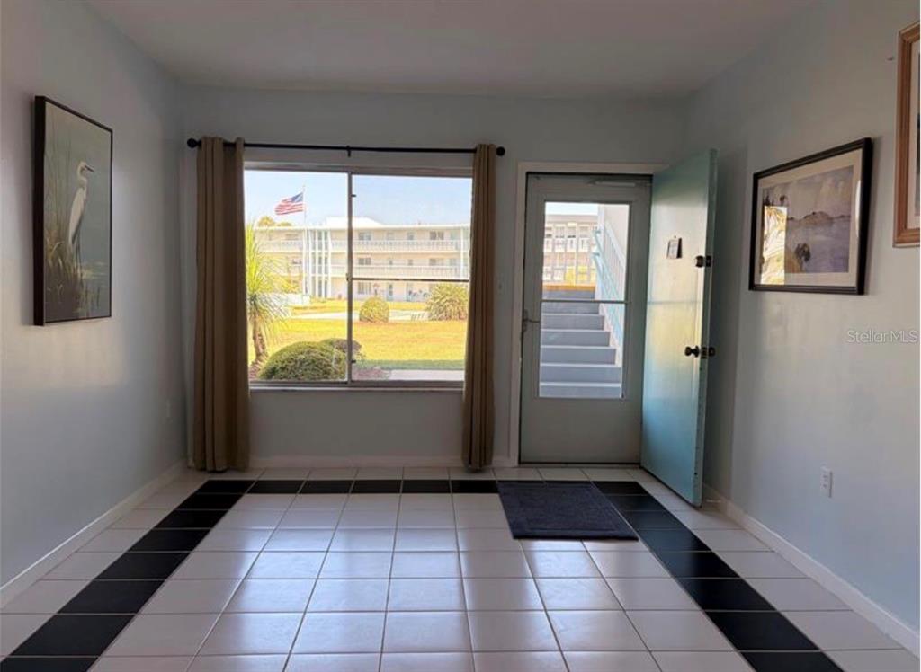 An interior room with light blue walls, white and black tiled flooring, and a window — 3009 N HALIFAX AVENUE UNIT 2, DAYTONA BEACH, FL