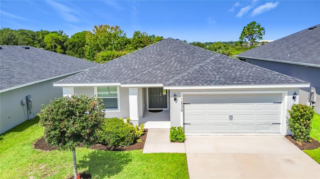 A single-story house with a gray roof, white exterior, and a two-car garage — 1235 MOUNTAIN FLOWER LANE, DAVENPORT, FL