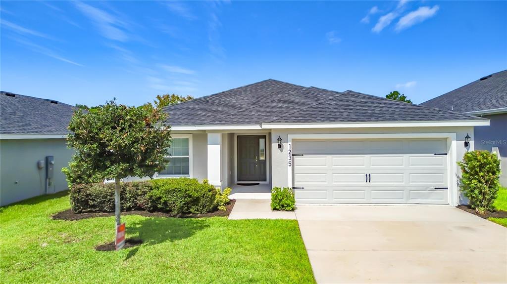 An aerial view shows the front exterior of a single-story house with a gray roof — 1235 MOUNTAIN FLOWER LANE, DAVENPORT, FL