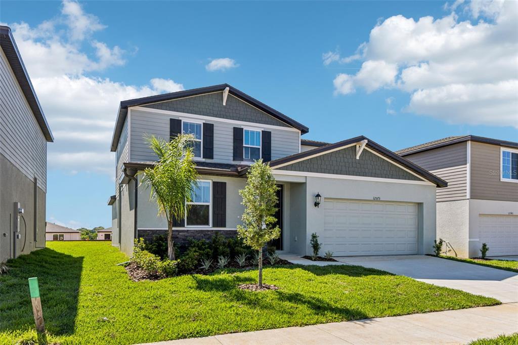 A two-story suburban house features gray siding, stone accents, and a two-car garage — 12573 HOMELAND DRIVE, DADE CITY, FL