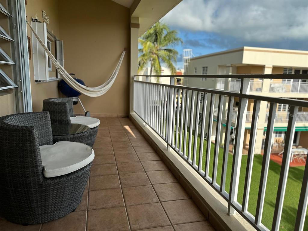 A balcony with tiled flooring, two wicker chairs, a hammock, and a metal railing — 368 CAMINO LAS PICUAS UNIT 3209, RIO GRANDE, PR