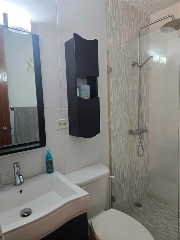A bathroom features a white sink, a dark wall cabinet, a toilet, and a glass-enclosed shower — 368 CAMINO LAS PICUAS UNIT 3209, RIO GRANDE, PR