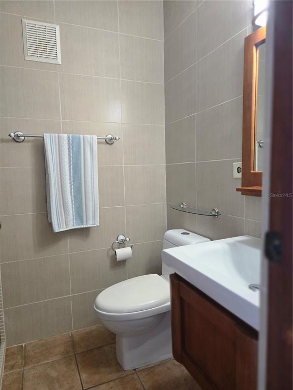 A small bathroom features beige tiled walls, a wooden vanity, and a white toilet — 368 CAMINO LAS PICUAS UNIT 3209, RIO GRANDE, PR