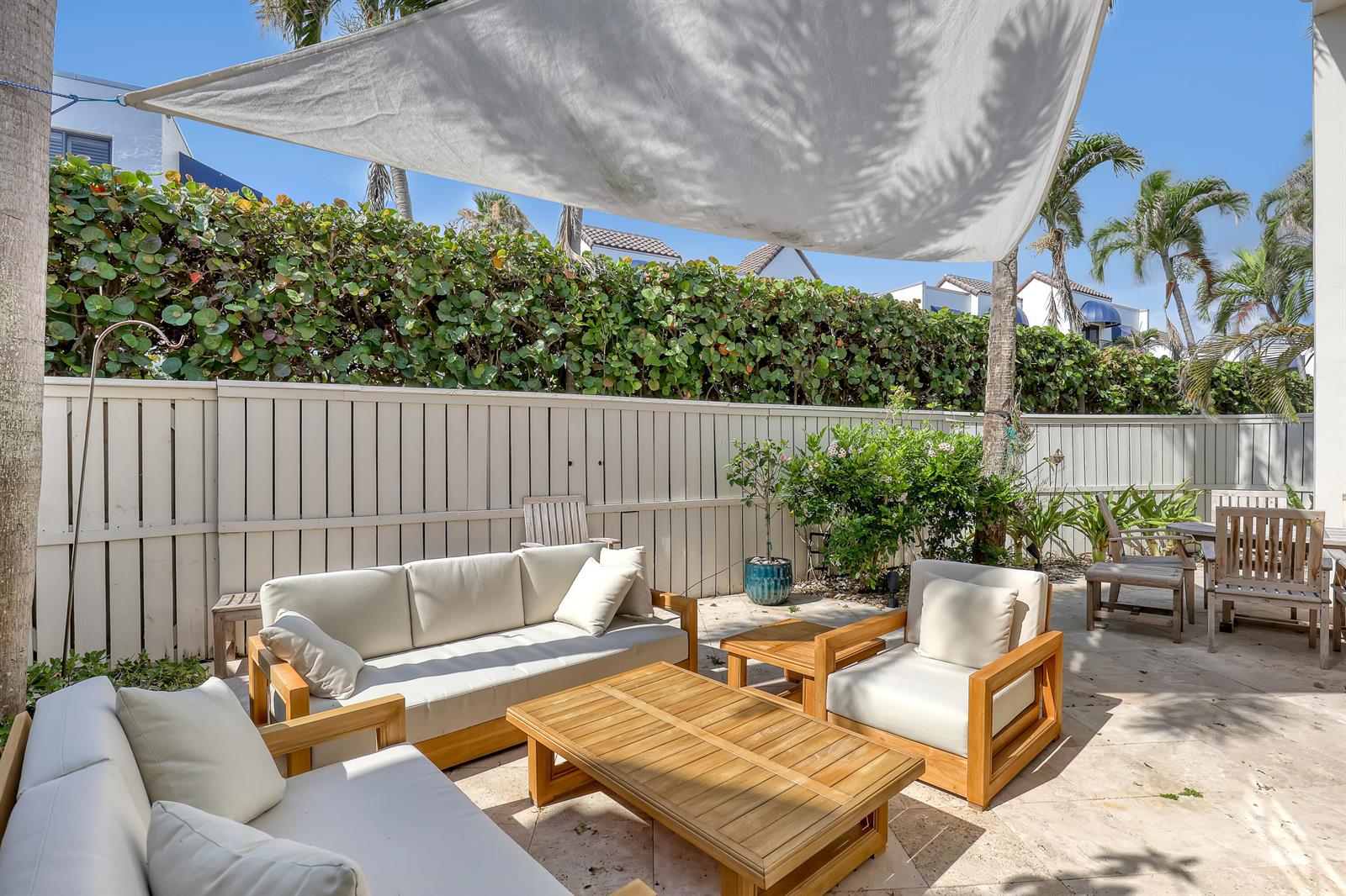 A patio features outdoor wooden furniture with white cushions under a large white shade sail — 220 Celestial Way # 6, Juno Beach FL 33408, JUNO BEACH, FL