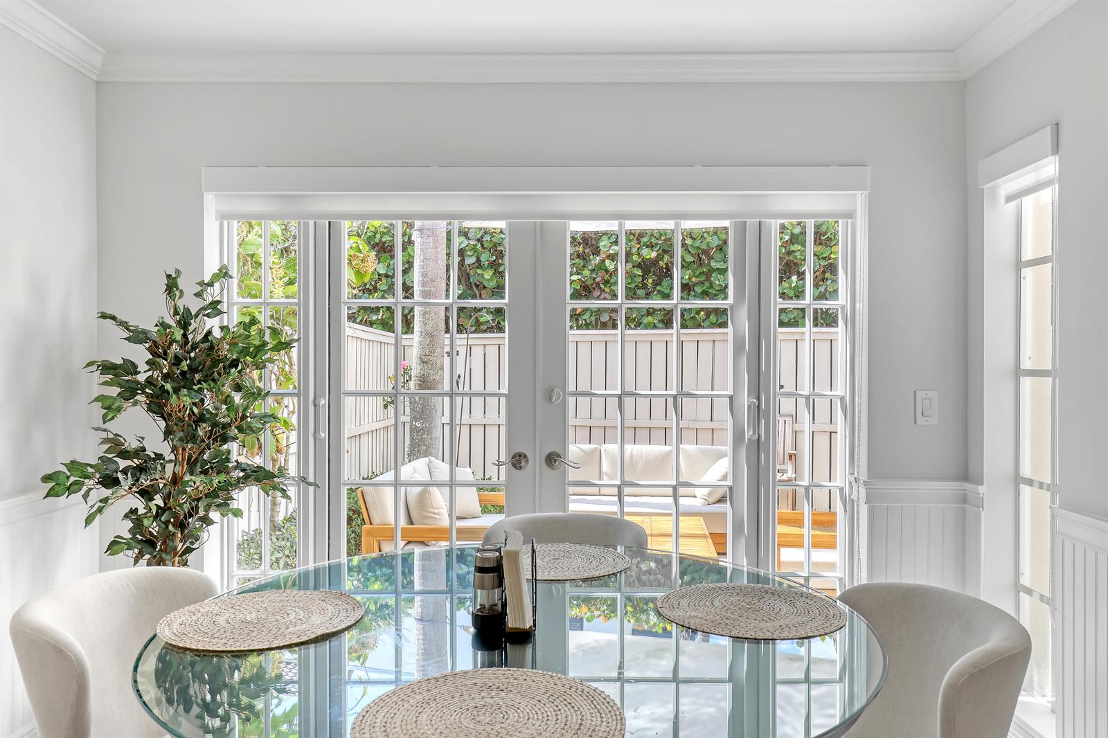 A dining room features a glass-topped table, upholstered chairs, and French doors opening to a patio — 220 Celestial Way # 6, Juno Beach FL 33408, JUNO BEACH, FL