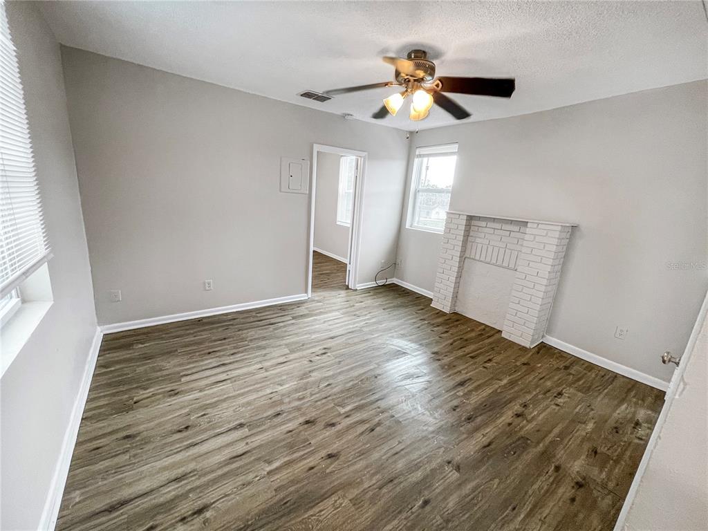 An empty room features light gray walls, wood-look flooring, a ceiling fan, and a fireplace — 321 W IANTHE STREET UNIT 6, TAVARES, FL