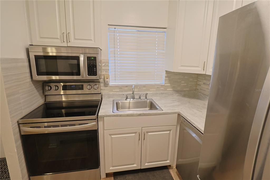 A kitchen features white cabinets, stainless steel appliances, a sink, and light-colored countertops — 5955 PALM LANE UNIT A33, BRADENTON, FL