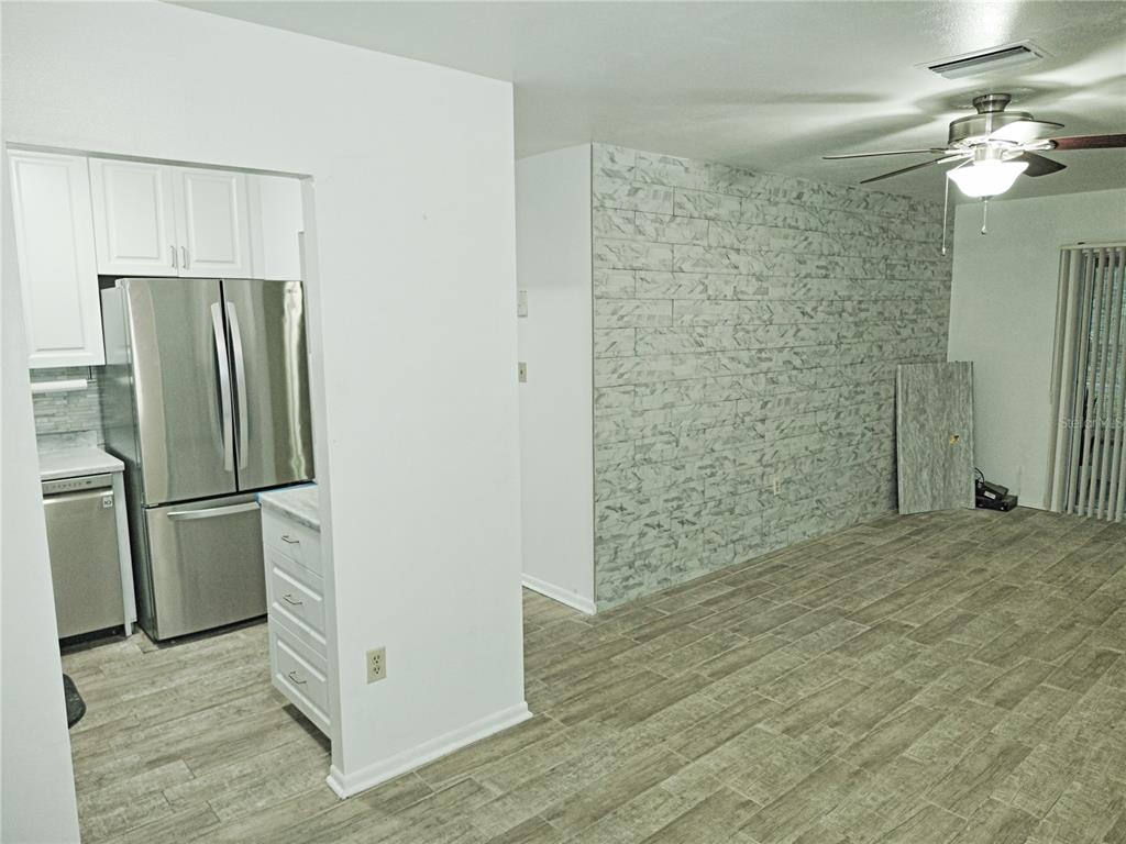 A kitchen with stainless steel appliances opens into a living area with faux-stone wall paneling — 5955 PALM LANE UNIT A33, BRADENTON, FL