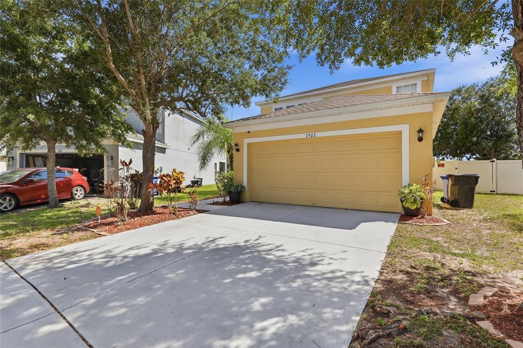 A yellow two-story house with a two-car garage and a concrete driveway — 7902 CARRIAGE POINTE DR, GIBSONTON, FL