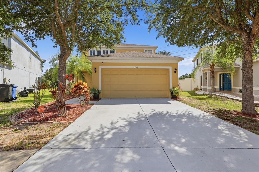 A two-story yellow house with a two-car garage and a concrete driveway — 7902 CARRIAGE POINTE DR, GIBSONTON, FL