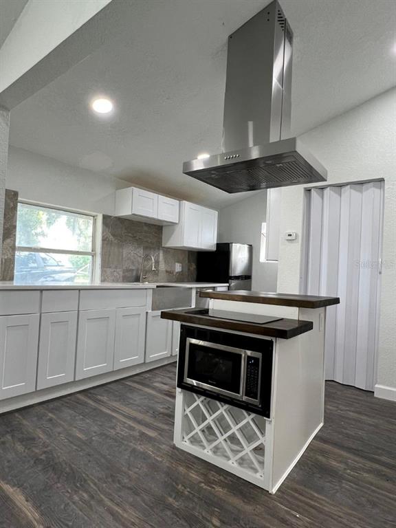 A kitchen features white cabinets, a stainless steel range hood, and a central island — 1526 LAKEWOOD ROAD, DAVENPORT, FL