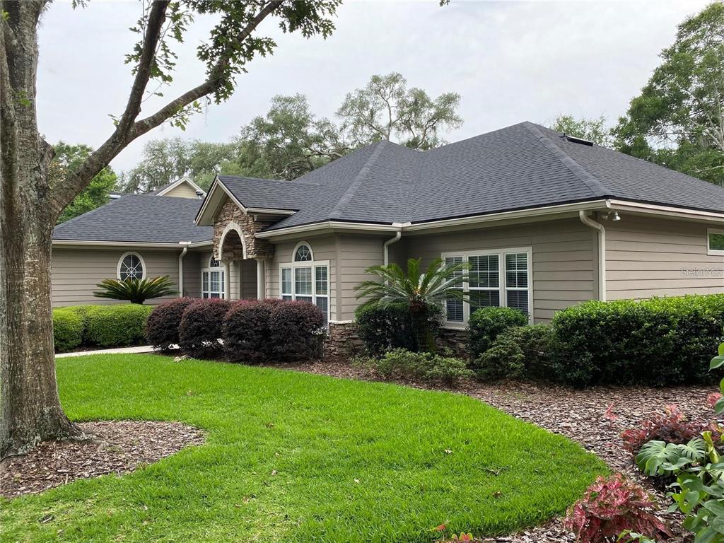 A single-story house with tan siding, a stone entryway, and a dark shingled roof — 4072 NW 37TH TERRACE, GAINESVILLE, FL