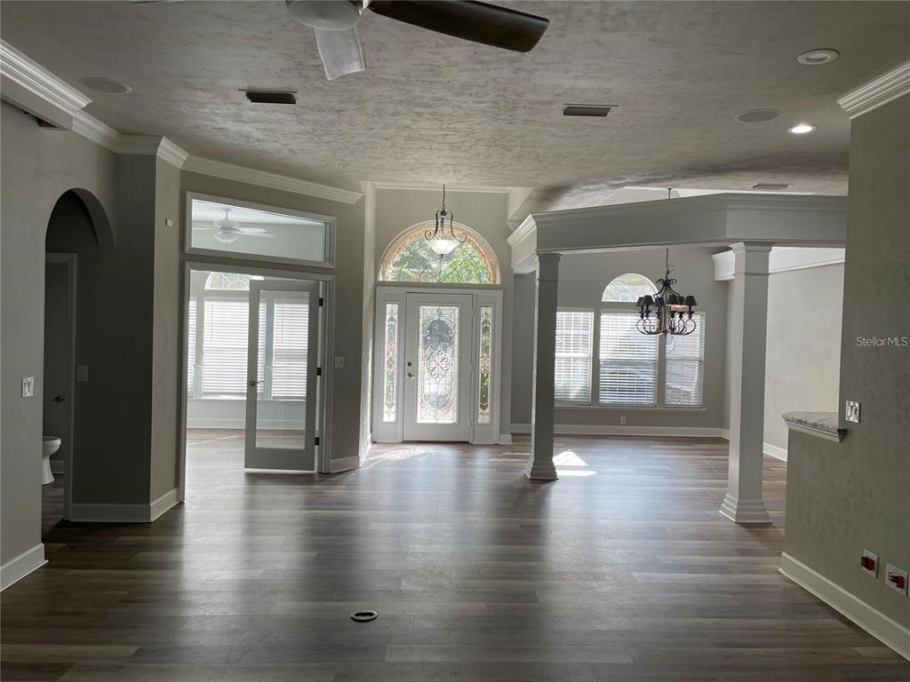 A spacious living area features wood-look flooring, white columns, and a decorative glass front door — 4072 NW 37TH TERRACE, GAINESVILLE, FL