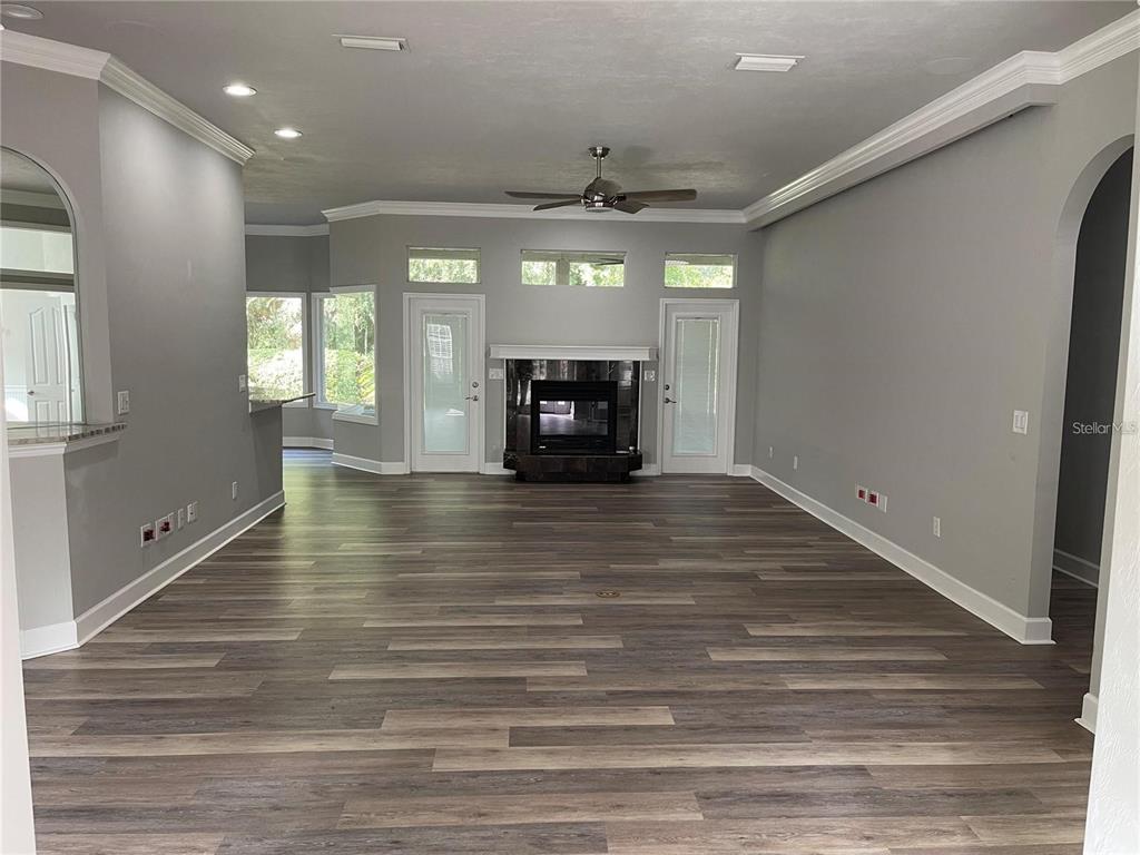 A spacious living room features gray walls, wood-look flooring, a fireplace, and a ceiling fan — 4072 NW 37TH TERRACE, GAINESVILLE, FL