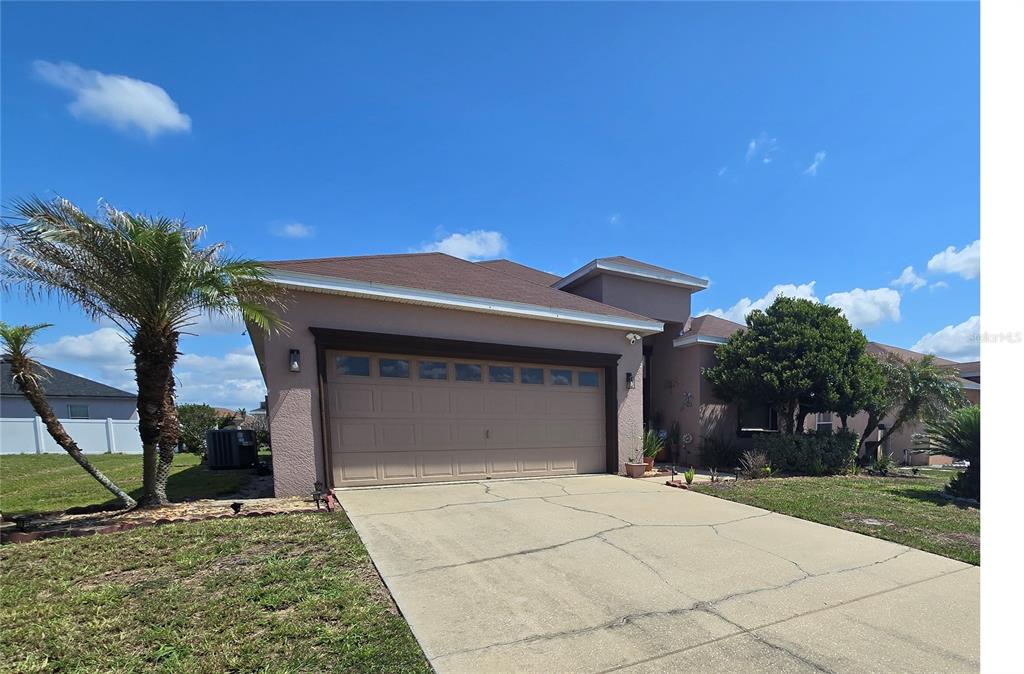 A single-story house with a tan stucco exterior, a two-car garage, and a palm tree — 219 CLOVERDALE ROAD, WINTER HAVEN, FL