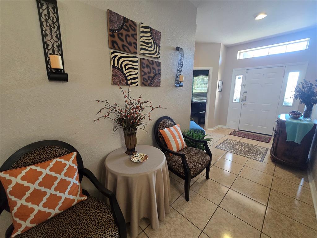 An entryway features tiled floors, two leopard-print chairs with orange pillows, and a small table — 219 CLOVERDALE ROAD, WINTER HAVEN, FL
