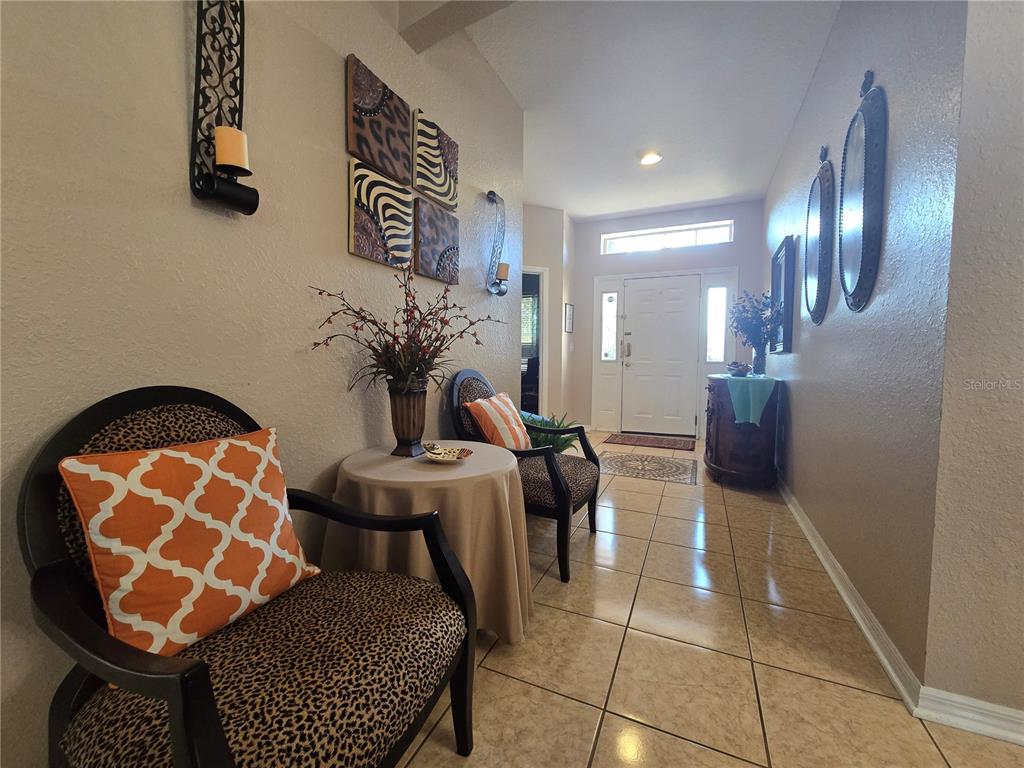 A tiled entryway features two leopard-print chairs, a small round table, and wall-mounted mirrors — 219 CLOVERDALE ROAD, WINTER HAVEN, FL