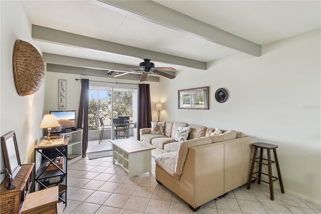 A living room features a beige sectional sofa, tile flooring, and exposed ceiling beams — 1703 CLUB CIRCLE, LAKESHORE, FL